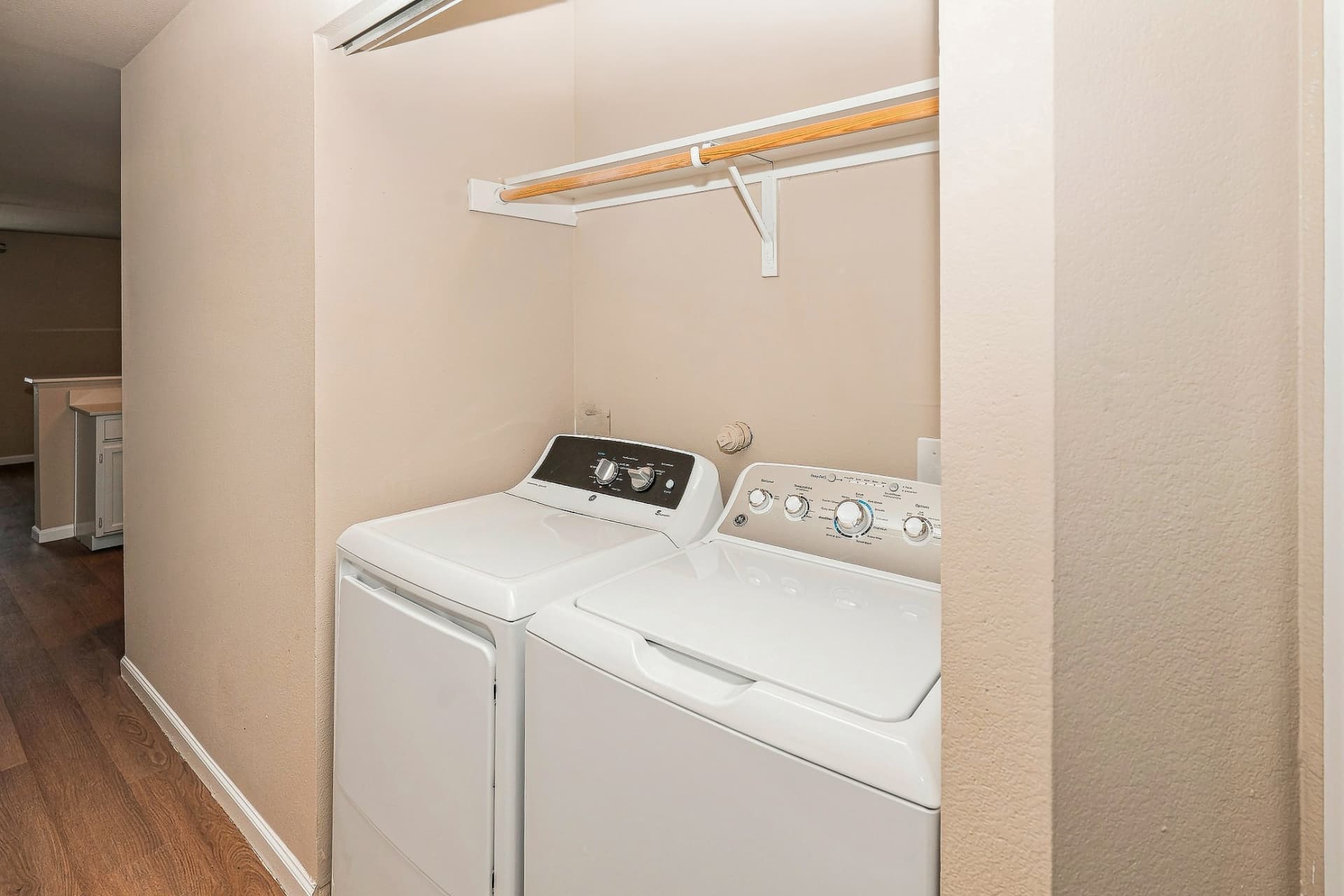 Renovated in-home laundry room with washer, dryer, and hanging rod