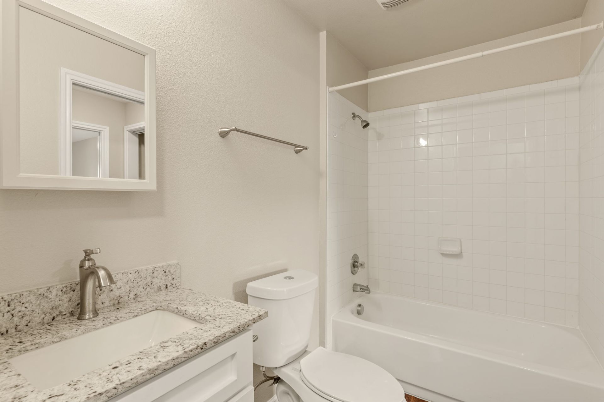Full bathroom with granite vanity and tiled tub surround