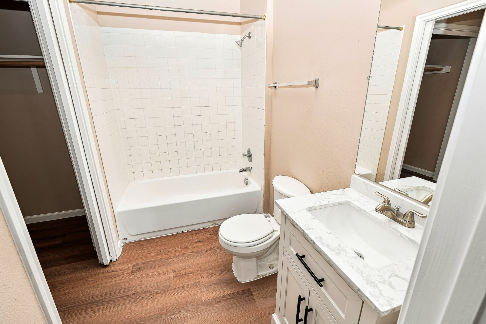 Renovated primary bathroom with white vanity, stone-look counter, and tub/shower