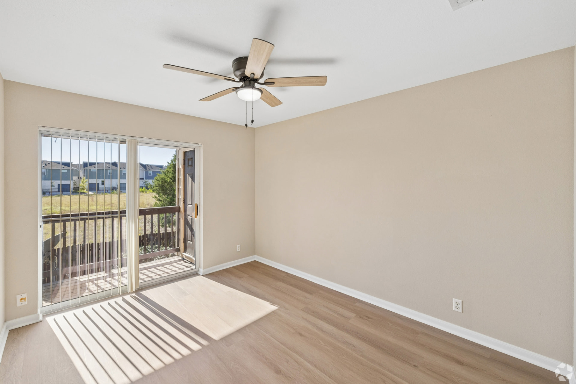 Renovated bedroom with a wooden ceiling fan and a sliding glass door opening to the balcony
