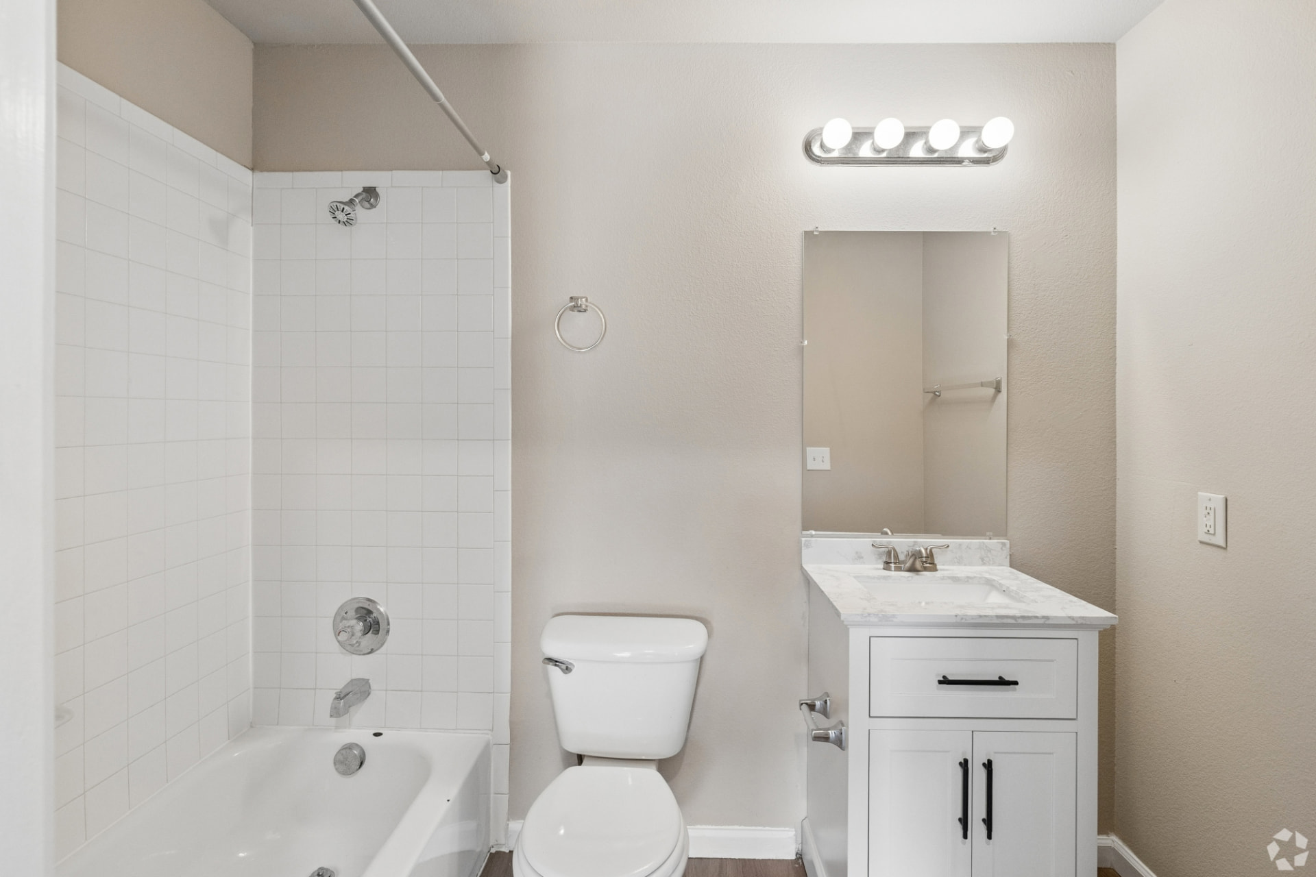 Second renovated bathroom with a single-sink white vanity, tub/shower combo, and four-light mirror fixture