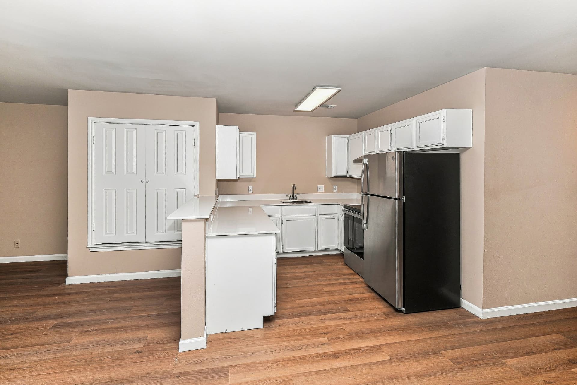 Renovated kitchen with white cabinets, light stone-look counters, and stainless appliances