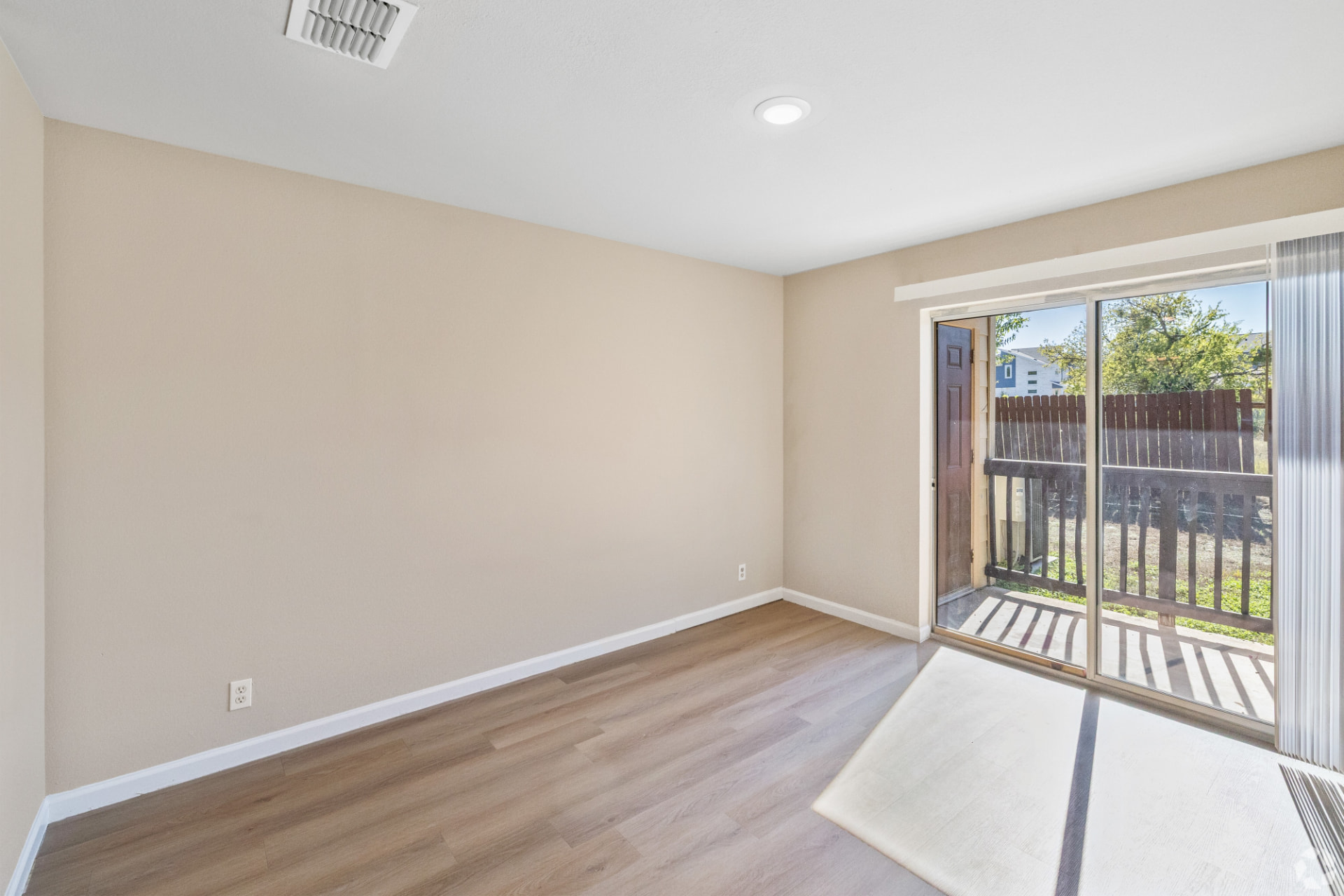 Renovated second bedroom with recessed lighting and a sliding glass door to the private patio