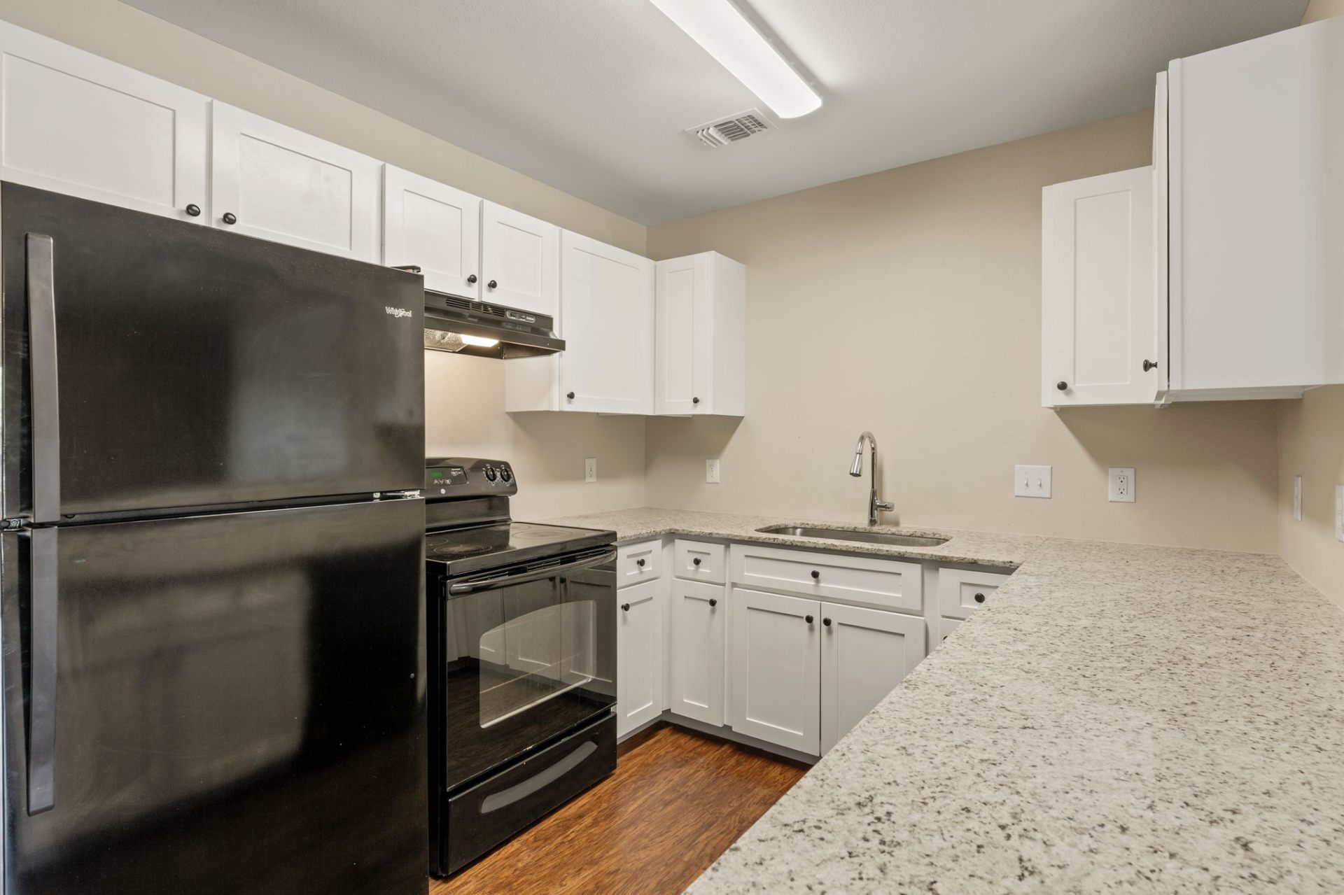 Full kitchen with white shaker cabinets, granite counters, and black appliances