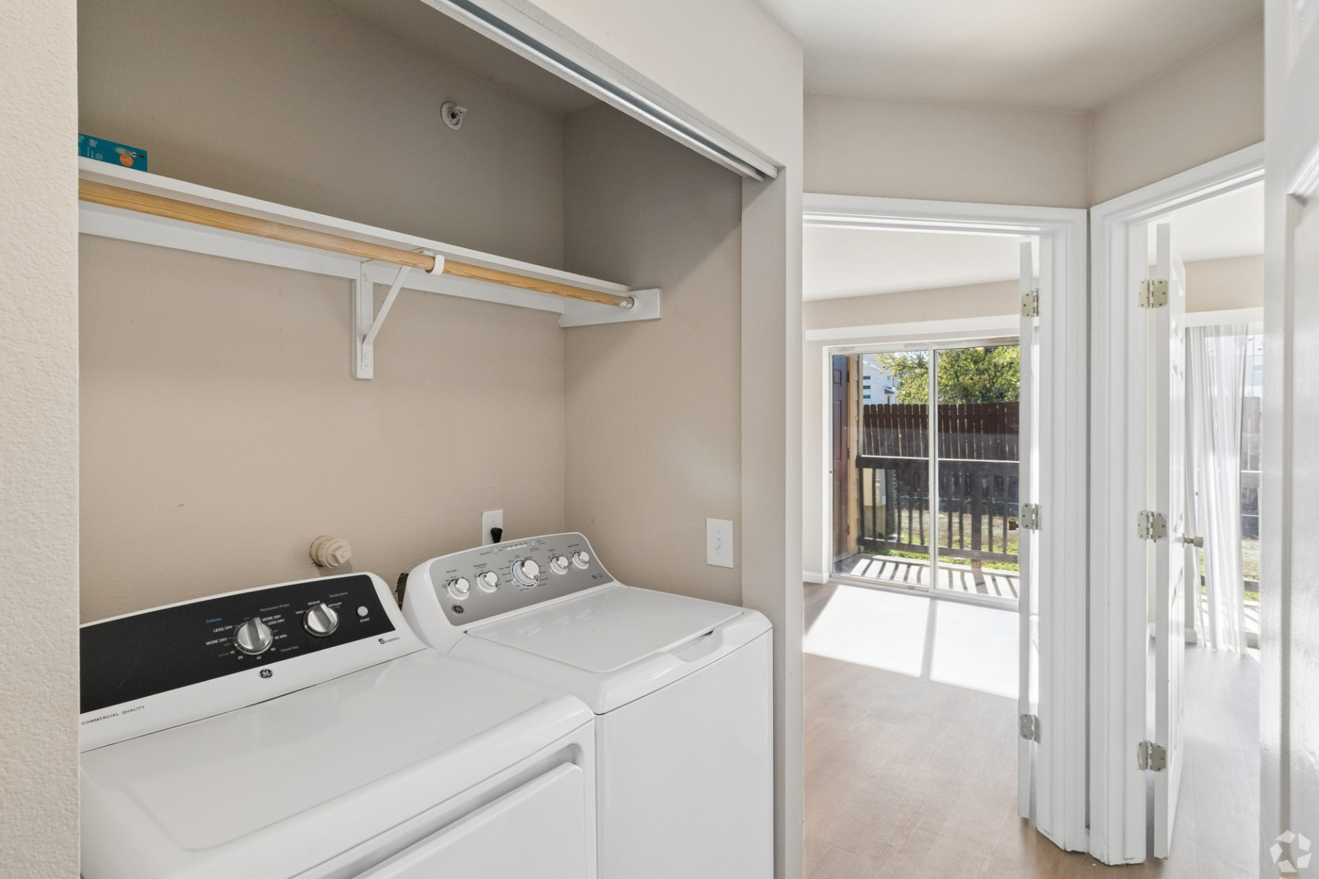 In-home laundry closet with a new GE washer and dryer and an overhead hanging rod