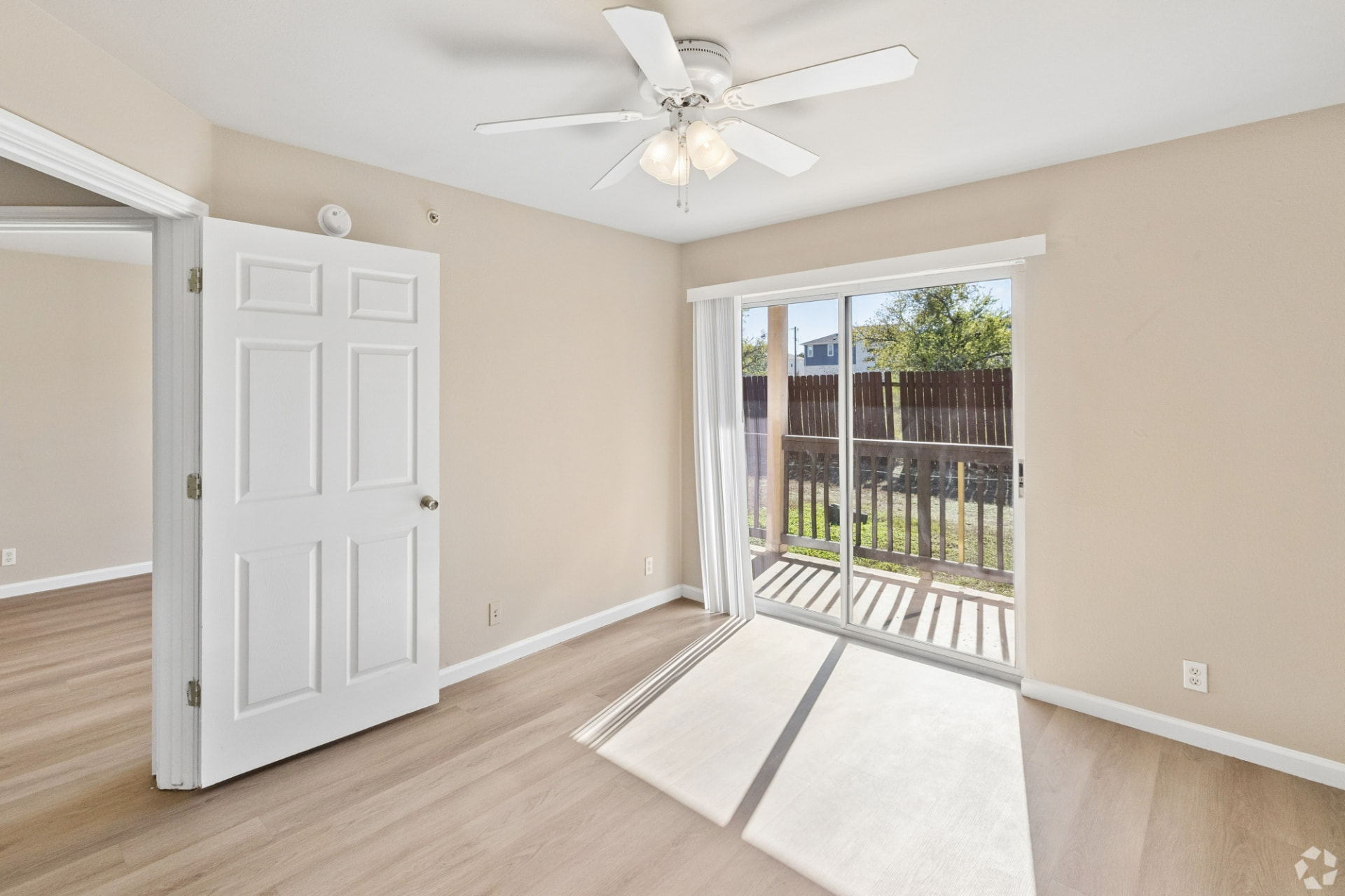 Renovated bedroom with a white ceiling fan and sliding glass door to the patio