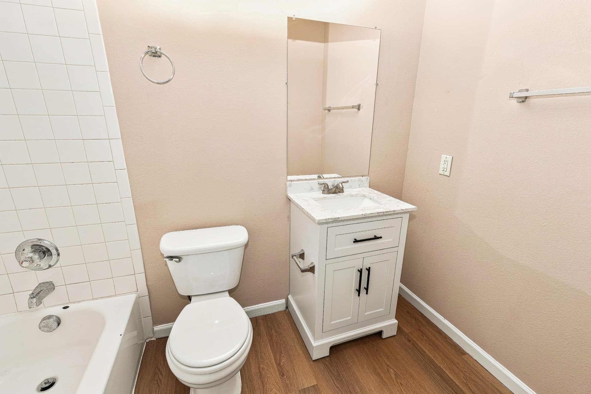 Renovated second bathroom with tub, white tile, and stone-look vanity