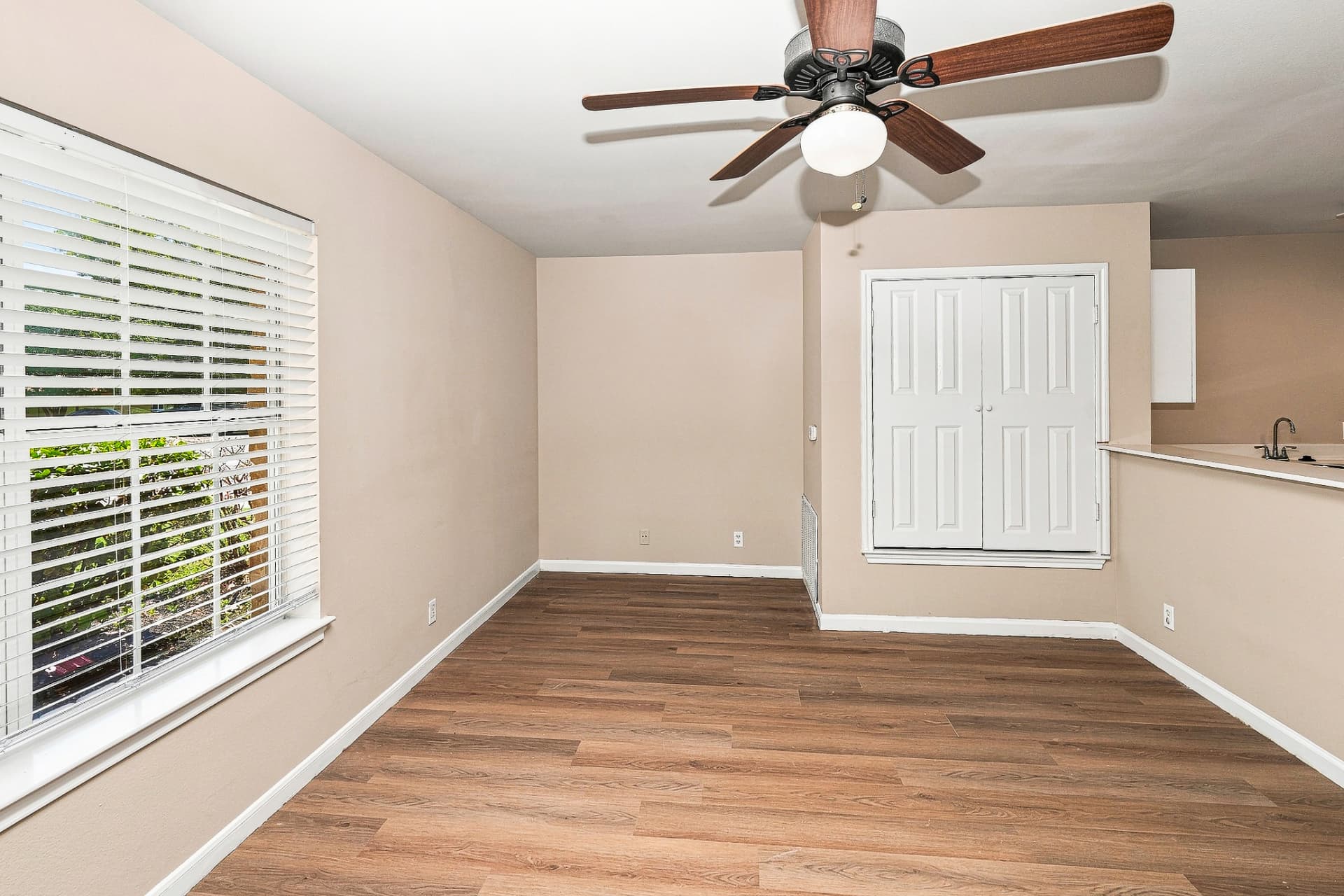 Renovated living room with wood-look flooring, ceiling fan, and open kitchen view