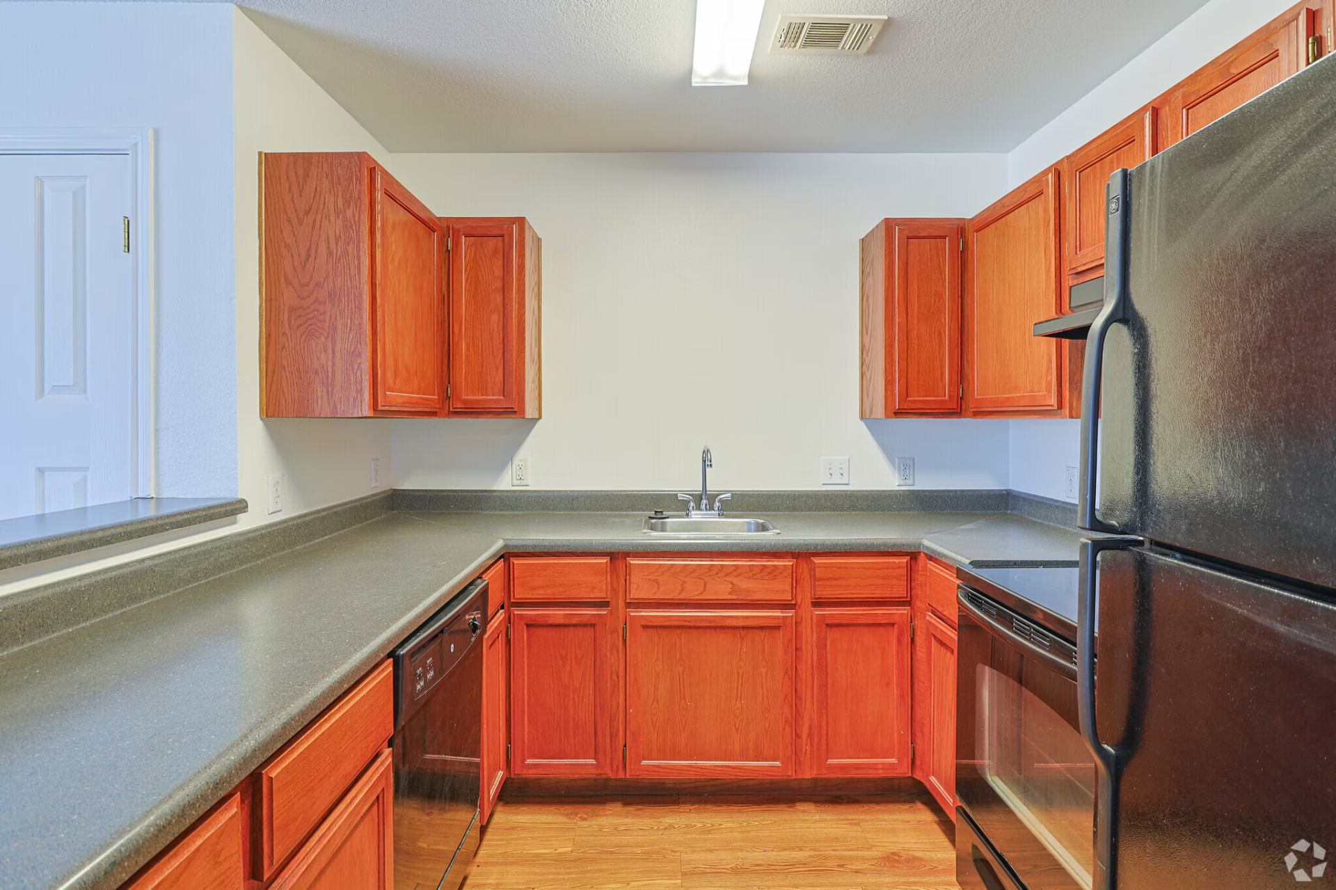 Classic-finish kitchen with oak cabinetry, dark laminate counters, and black appliances